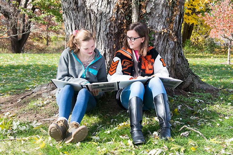 Two students sitting under a tree